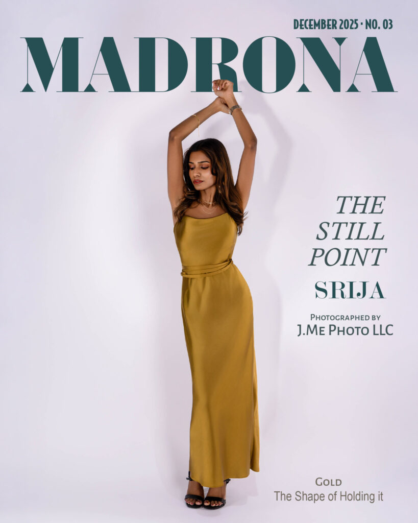 Srija in a gold satin gown, wrists crossed above her head against a pale wall, on the December 2025 cover of Madrona