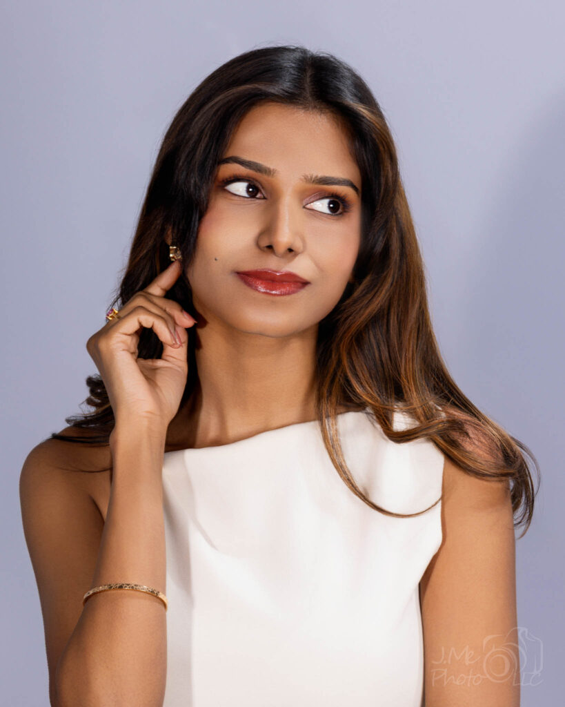 Close portrait of Srija in a white top against a pale lilac-grey ground